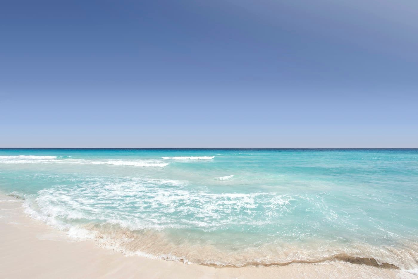 Turquoise waves washing onto a sandy beach in Cancún, Mexico