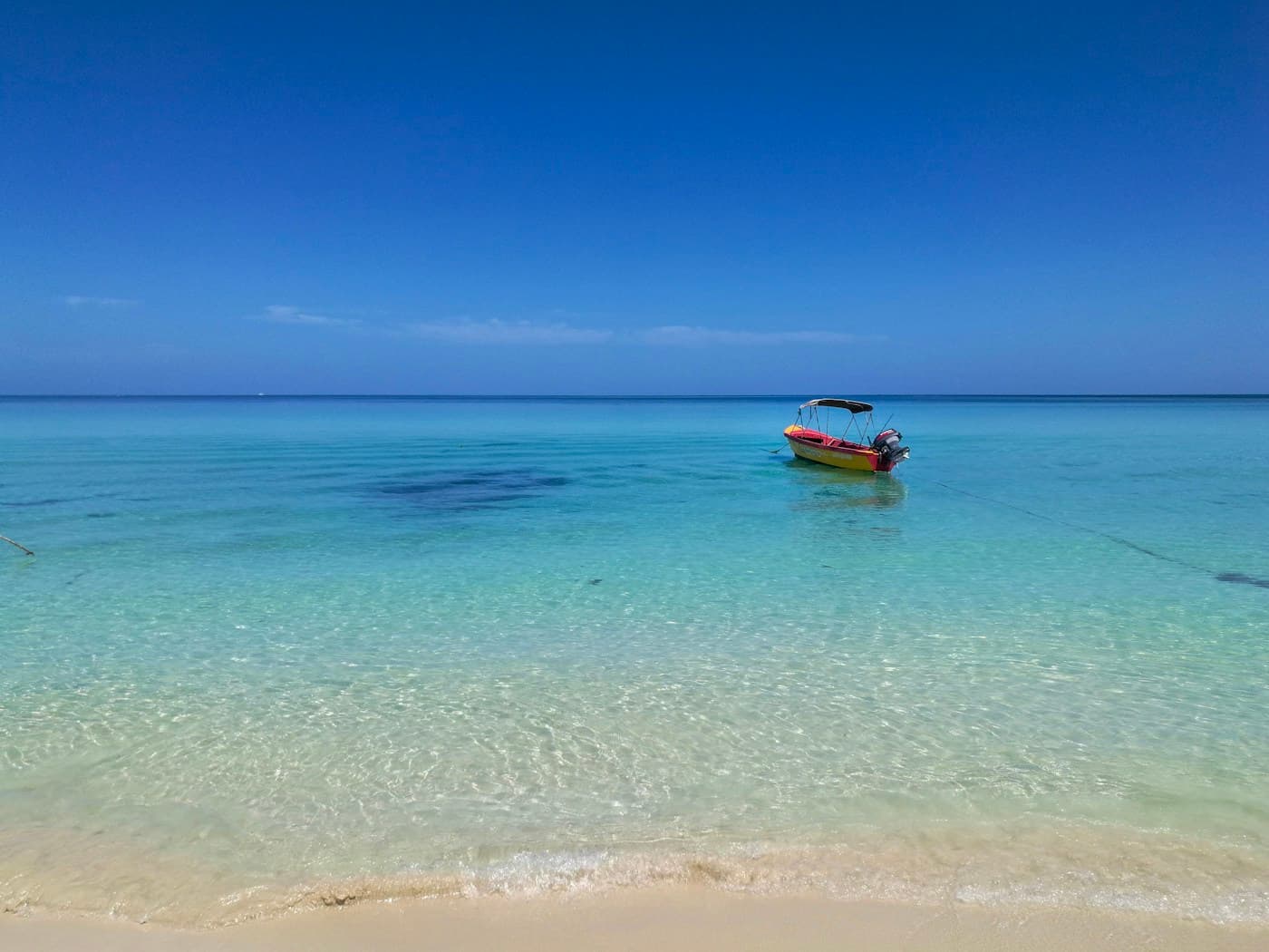 A boat in clear turquoise water off Seven Mile Beach in Negril, Jamaica